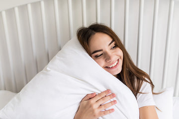  Save Download Preview Relaxed sensual happy young woman sitting on bed and hugging pillow