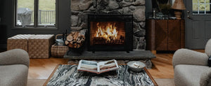 Cozy hygge living room with a fireplace, a book on a marble table, and two plush armchairs.