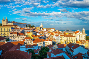 Scenic aerial landscape of Lisbon rooftops, highlighting historic architecture and distant cathedral.